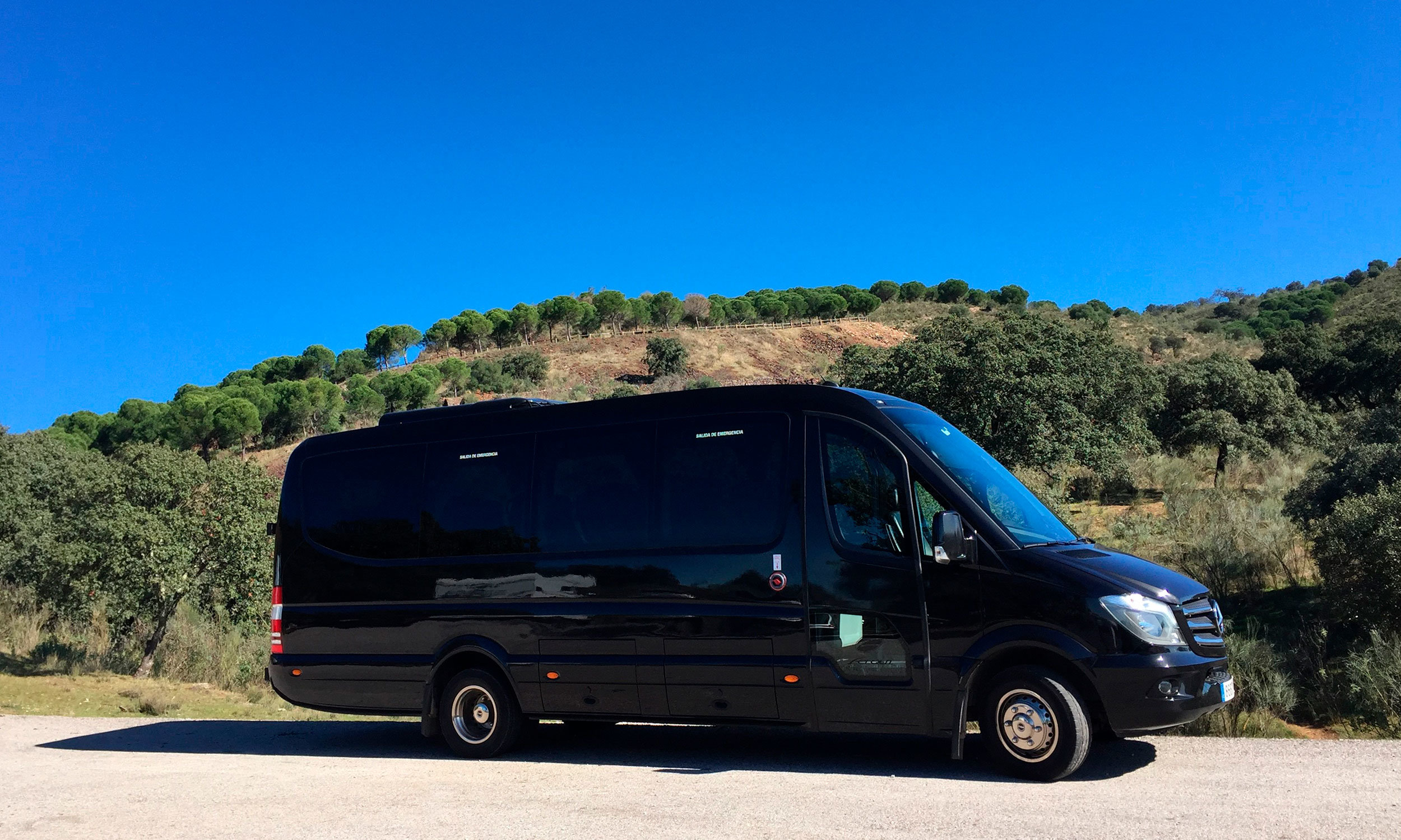 Microbús con 19 plazas de la empresa de autocares Olid Bus Travel de Valladolid aparcado junto a montaña