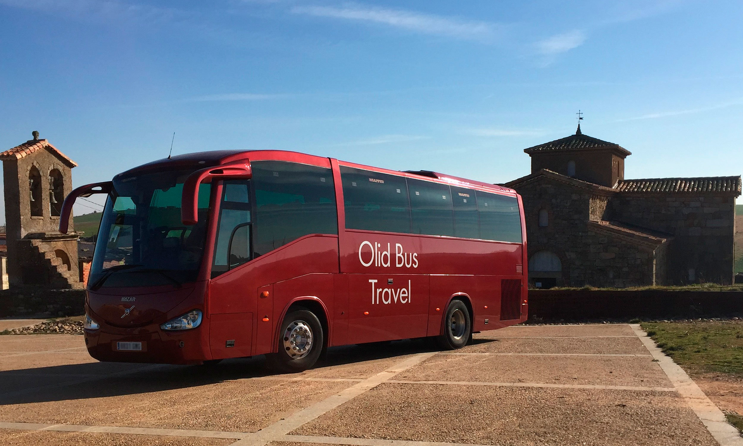 Microbús con 43 plazas de la empresa de autocares Olid Bus Travel de Valladolid frente a iglesia